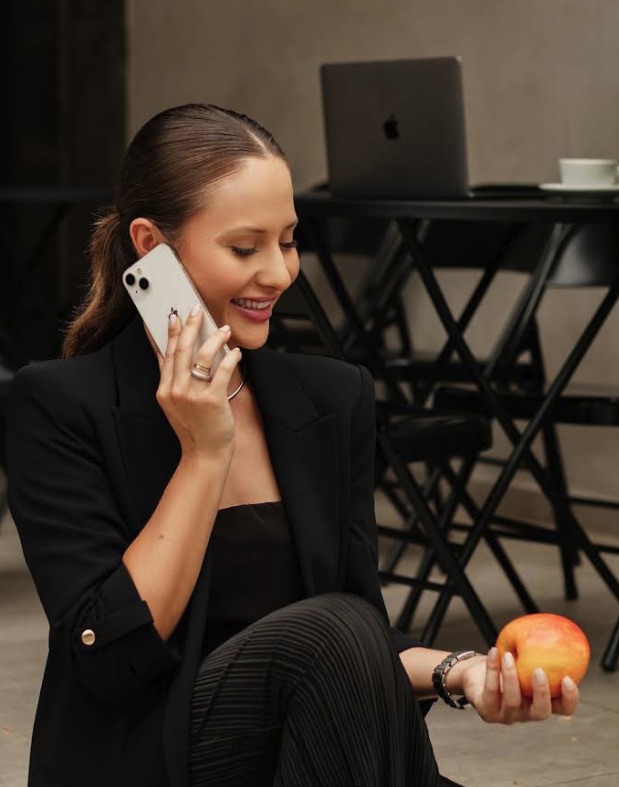 Victória de Souza ao telefone, segurando uma maçã.