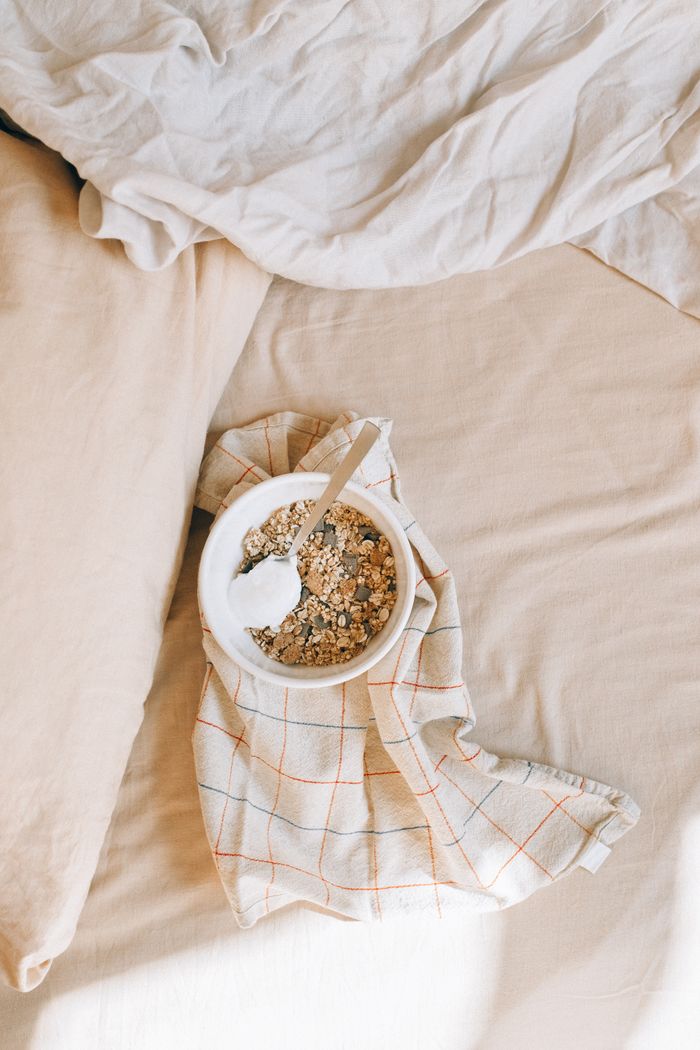 Tigela de granola e frutas sobre tecido de linho claro.